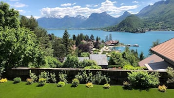 Een vakantiehuis aan een meer met uitzicht op bergen, een steiger en een verzorgd gazon.