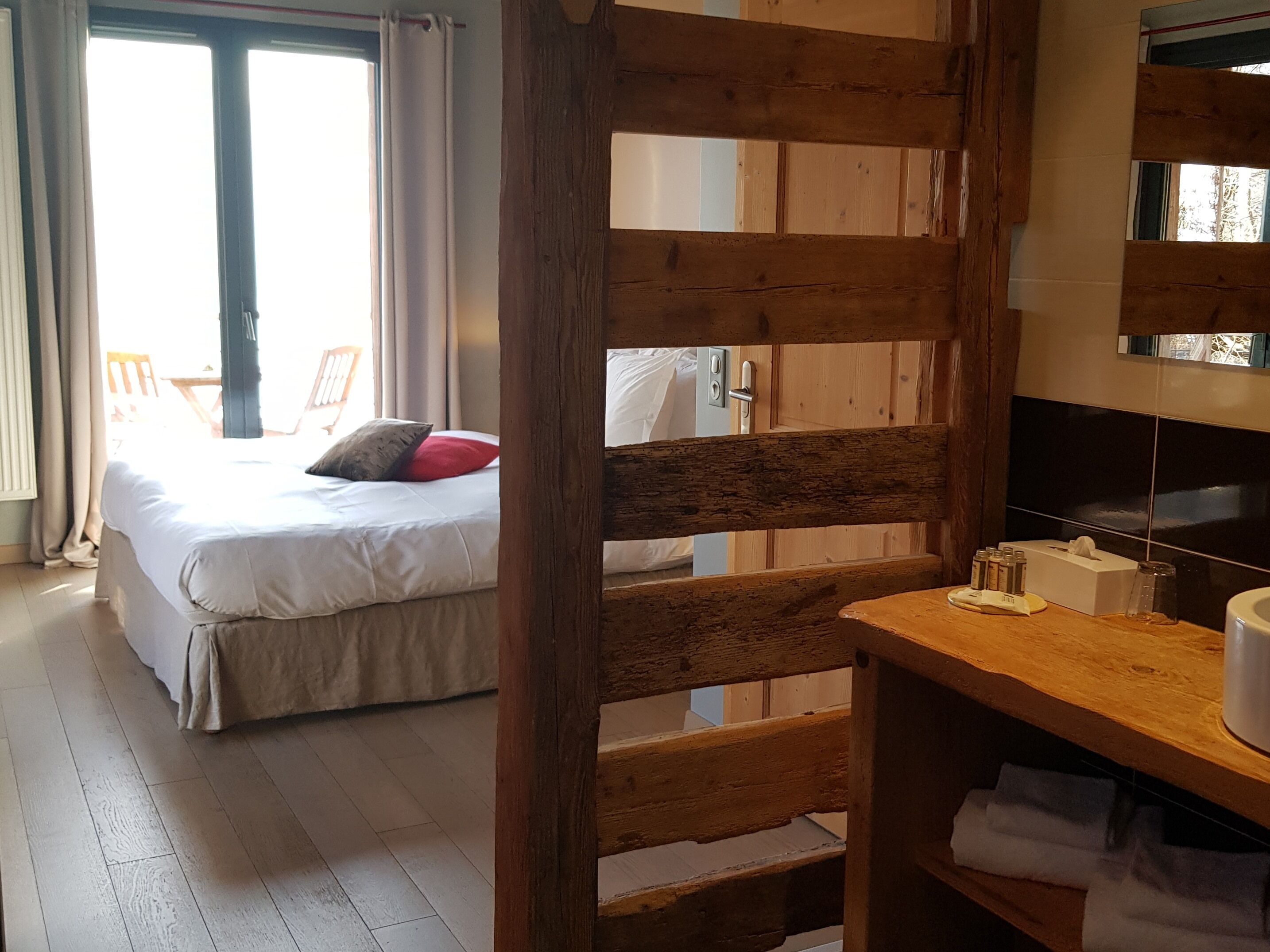A bedroom with a bed, wooden headboard, and a bedside table with a tissue box and a bottle.