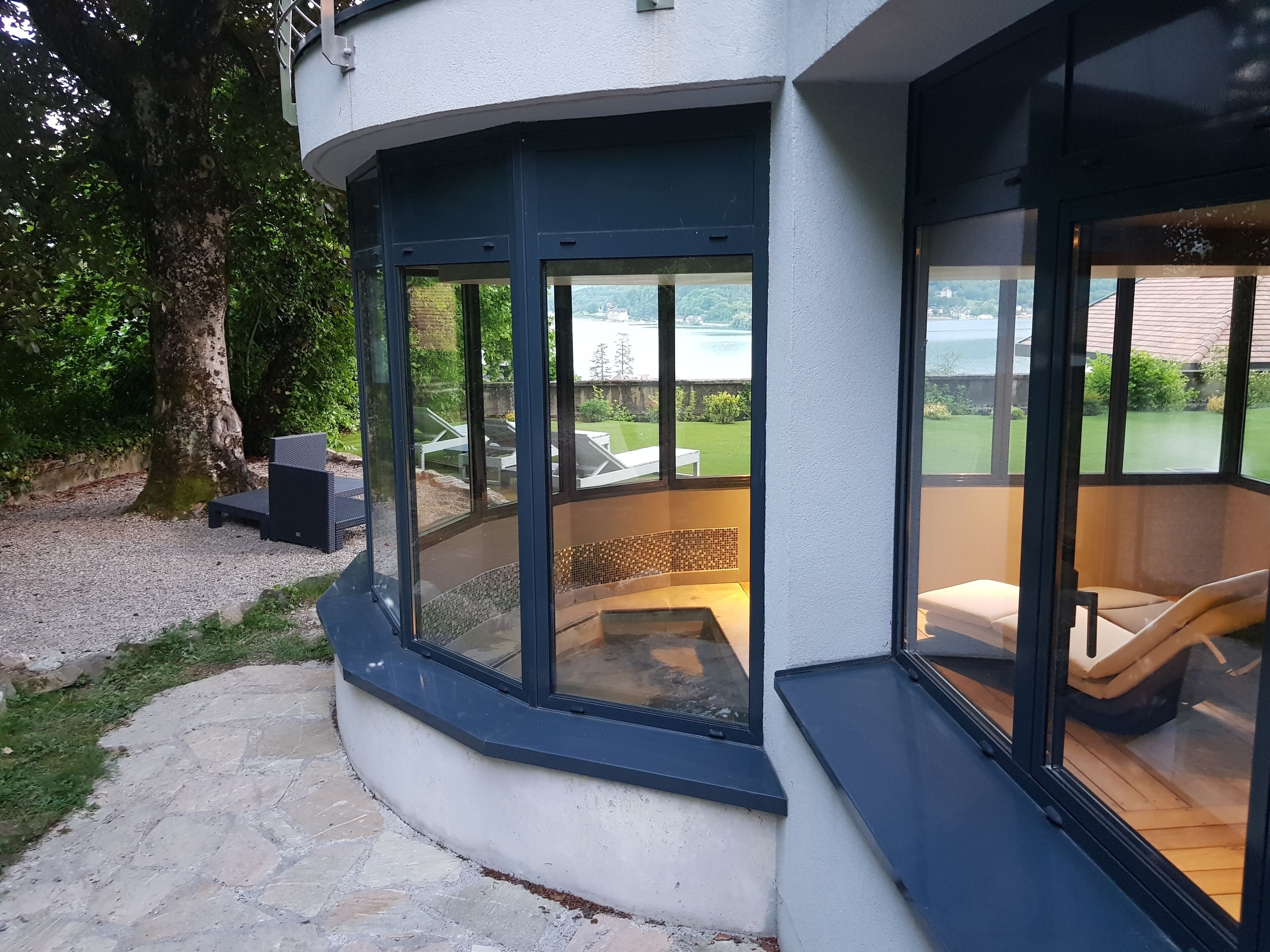 A modern outdoor seating area with a stone pathway leading to a glass-enclosed patio.