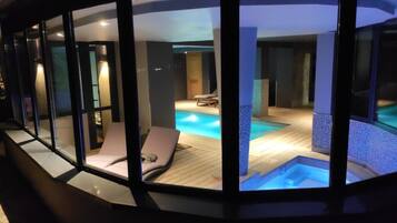 Een zwembadgedeelte met twee ligbedden en een jacuzzi.