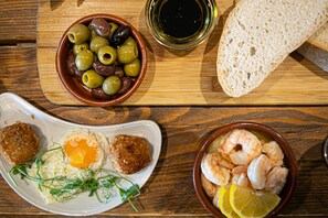 A wooden table with a variety of dishes including olives, shrimp, and bread. - Old Walls Vineyard (Teignmouth)