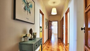 A hallway with wooden flooring, a desk with decorative items, and a framed artwork on the wall.
