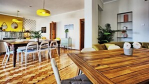 A dining area with a wooden table and chairs, a herringbone-patterned floor, and a yellow pendant light.