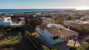 Zona residencial con casas, vista despejada del mar y un edificio destacado con tejado de azulejos.