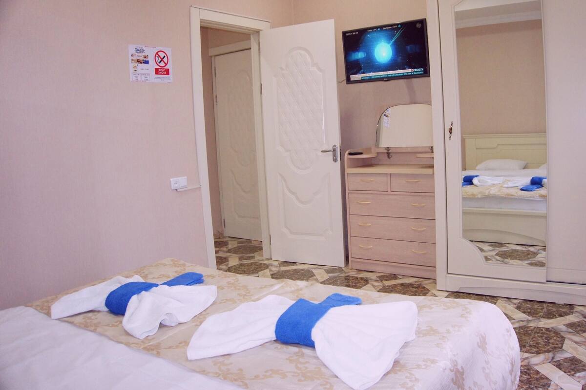 A hotel room with a bed, a wardrobe, and a television on the wall.