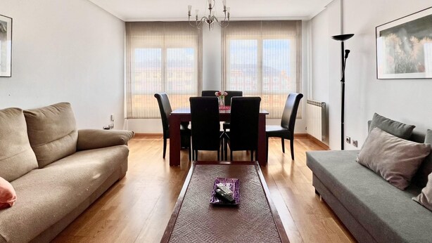 Un salon comprenant un canapé, une table à manger avec des chaises, un lustre et une lampe sur pied.