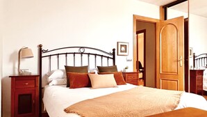 Une chambre à coucher bien rangée, avec un lit, des tables de chevet, une lampe et une armoire.