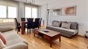 Un salon moderne comprenant un canapé, une table basse, une table à manger avec des chaises et deux tableaux encadrés accrochés au mur.