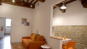 A cozy living room with a sofa, a small round table, and a stone wall.