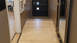A hallway with a black door, a large mirror, and a clock on the wall. - Hotel Franken an der Messe (Frankfurt)