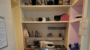 A compact kitchen with a refrigerator, sink, and a small trash bin. - Hotel Franken an der Messe (Frankfurt)
