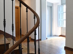 Un escalier en bois, avec des balustrades noires, menant à un palier.