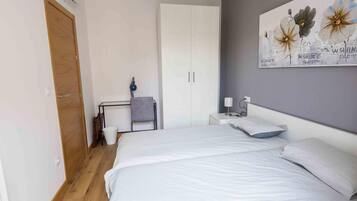 Un dormitorio con una cama grande, un escritorio, una silla, un armario y una lámpara fijada a la pared.