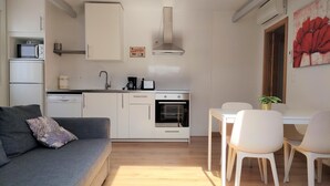 Eine kleine Küche mit weißen Schränken, einem eingebauten Ofen und einer Kaffeemaschine.