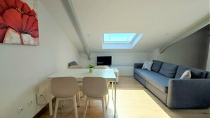 Eine moderne Loftwohnung mit Essbereich, einem grauen Sofa und einem Oberlicht.