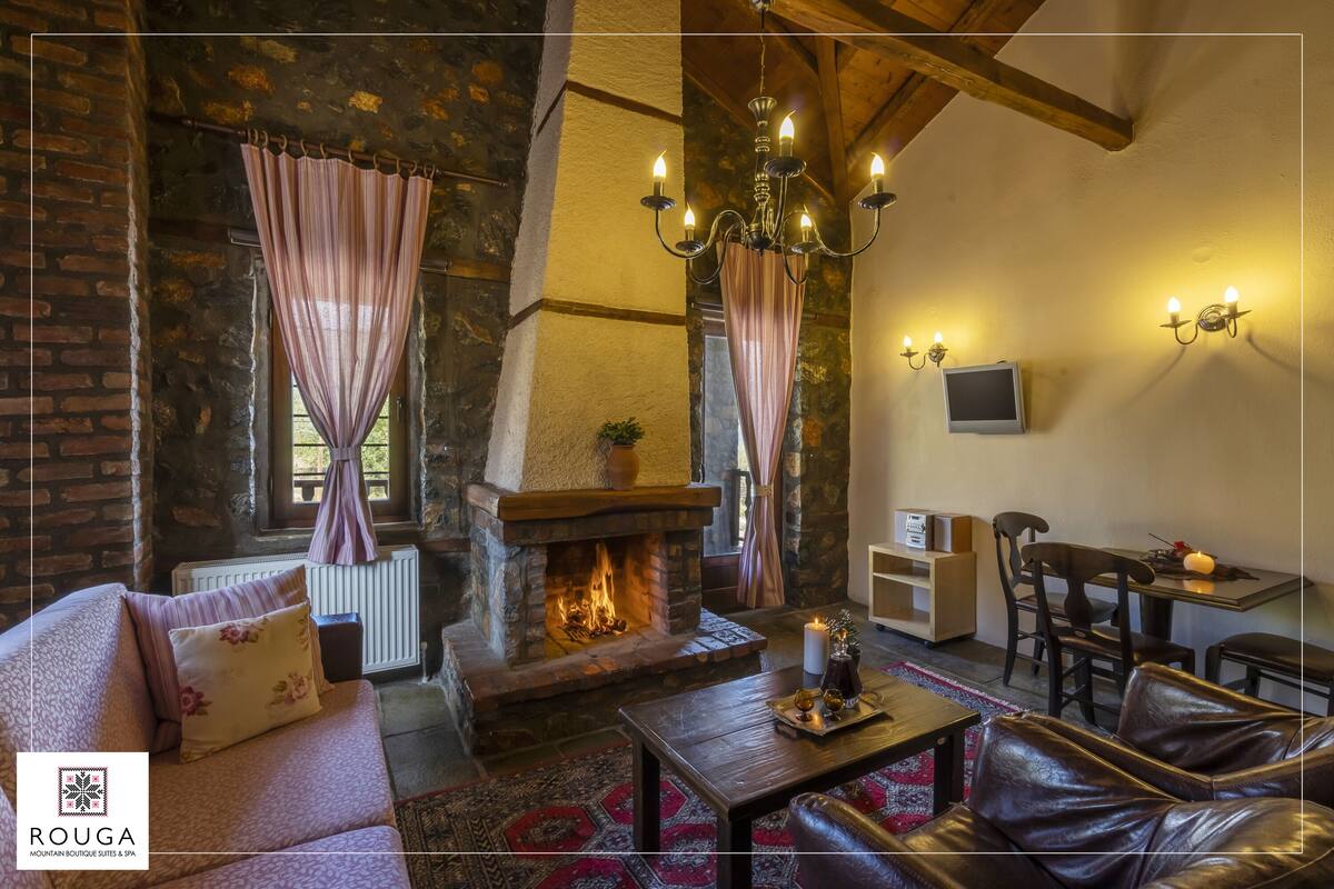 A cozy living room with a stone fireplace, leather sofa, and a dining area with a table and chairs.