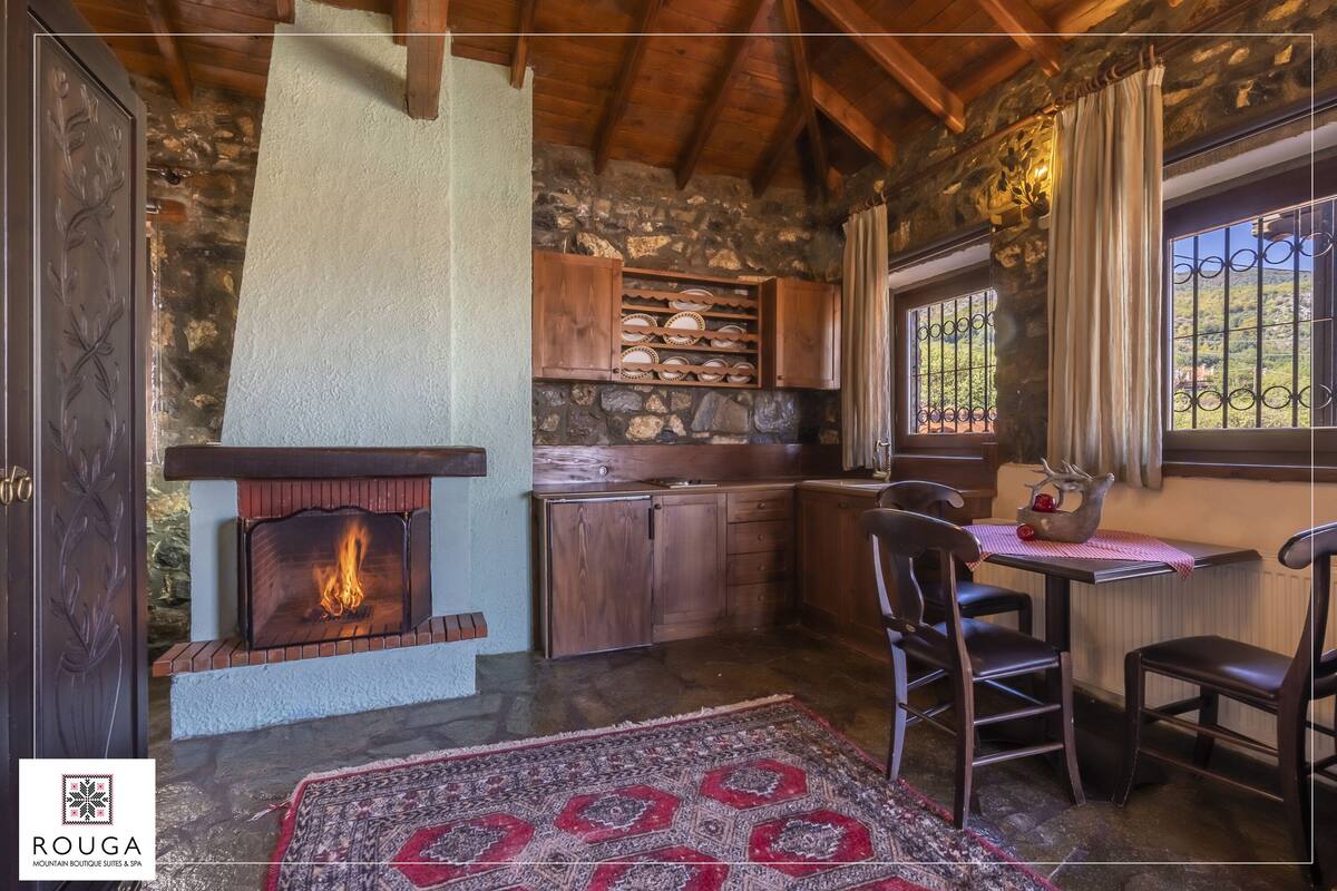 A cozy room with a stone fireplace, wooden cabinets, and a dining area with chairs.