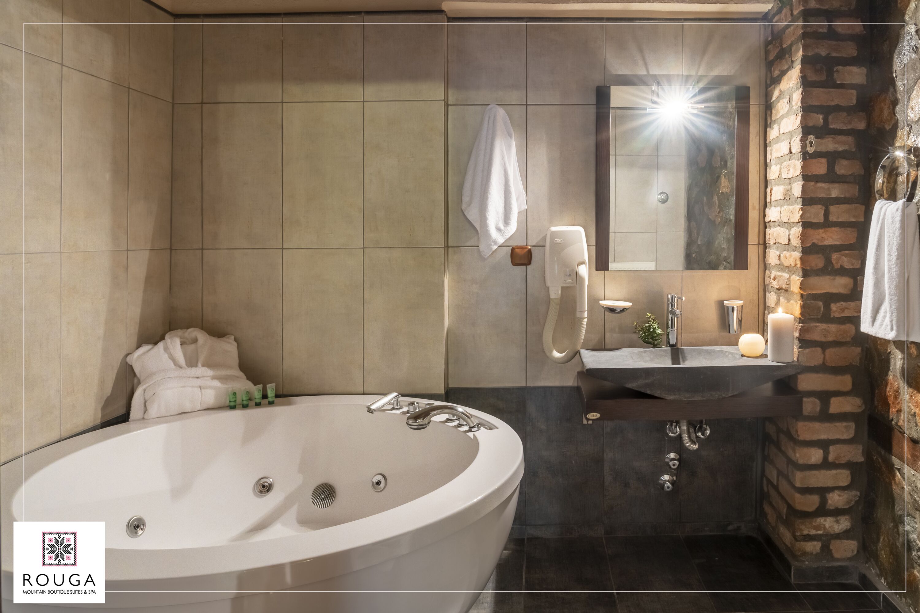 A modern bathroom with a large bathtub, a vanity with a mirror, and a stone accent wall.