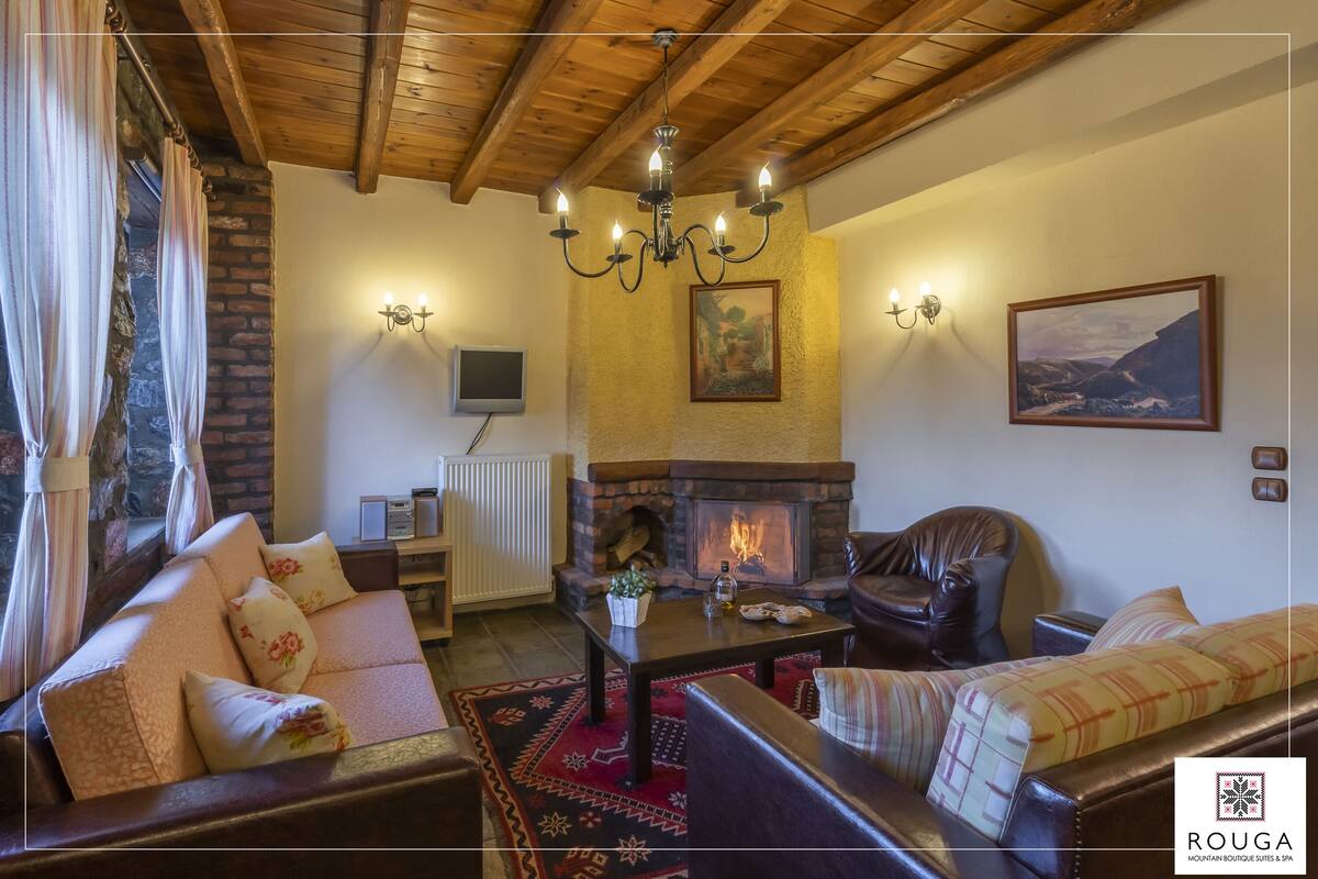 A cozy living room with a fireplace, leather sofas, a coffee table, and a chandelier.