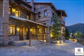 A stone building with a balcony and a Christmas tree, featuring a stone facade and wooden beams.
