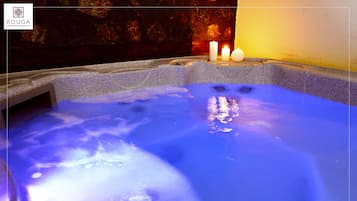 A hot tub with blue lighting and candles.