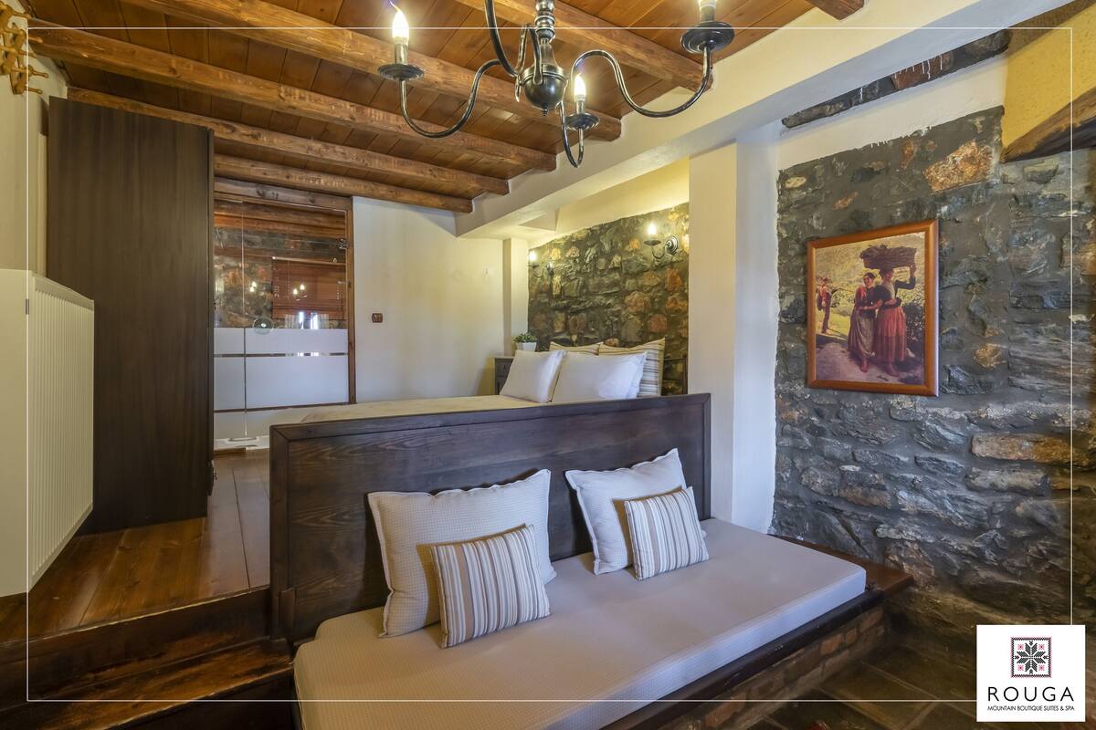 A bedroom with a wooden headboard, a stone accent wall, and a chandelier.