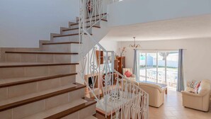 A spacious living area with a staircase leading to an upper floor. - Villa Gui by Gabi Miguel (Vale Rebelho)