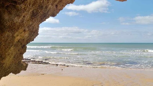 A beach with a large rock formation in the foreground and a view of the ocean. - Villa Gui by Gabi Miguel (Vale Rebelho)