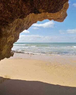 A beach with a large rock formation in the foreground and a view of the ocean.