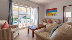 A living room with a sofa, armchairs, a coffee table, and a view of a pool and outdoor area through large sliding doors. - Villa Gui by Gabi Miguel (Vale Rebelho)
