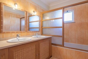 A bathroom with two sinks, wooden cabinetry, and frosted glass panels. - Villa Costa by Gabi Miguel (Sesmarias)