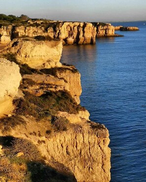 A coastal landscape with rocky cliffs and calm sea. - Villa Costa by Gabi Miguel (Sesmarias)