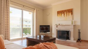 A living room with a sofa, a coffee table, a TV, and a fireplace. - Villa Costa by Gabi Miguel (Sesmarias)