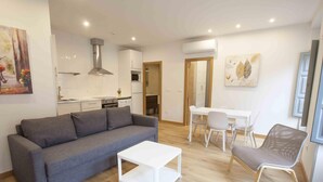Un salon moderne avec un canapé gris, une table basse blanche et un coin repas comprenant une table et des chaises blanches.