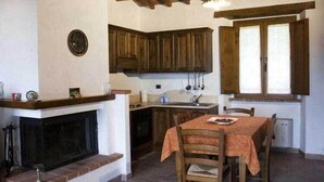 Uma cozinha rústica com armários de madeira, uma lareira e uma mesa de jantar com cadeiras.