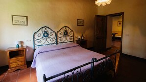 Un dormitorio con cama, mesita de noche, lámpara y un cuadro colgado en la pared.
