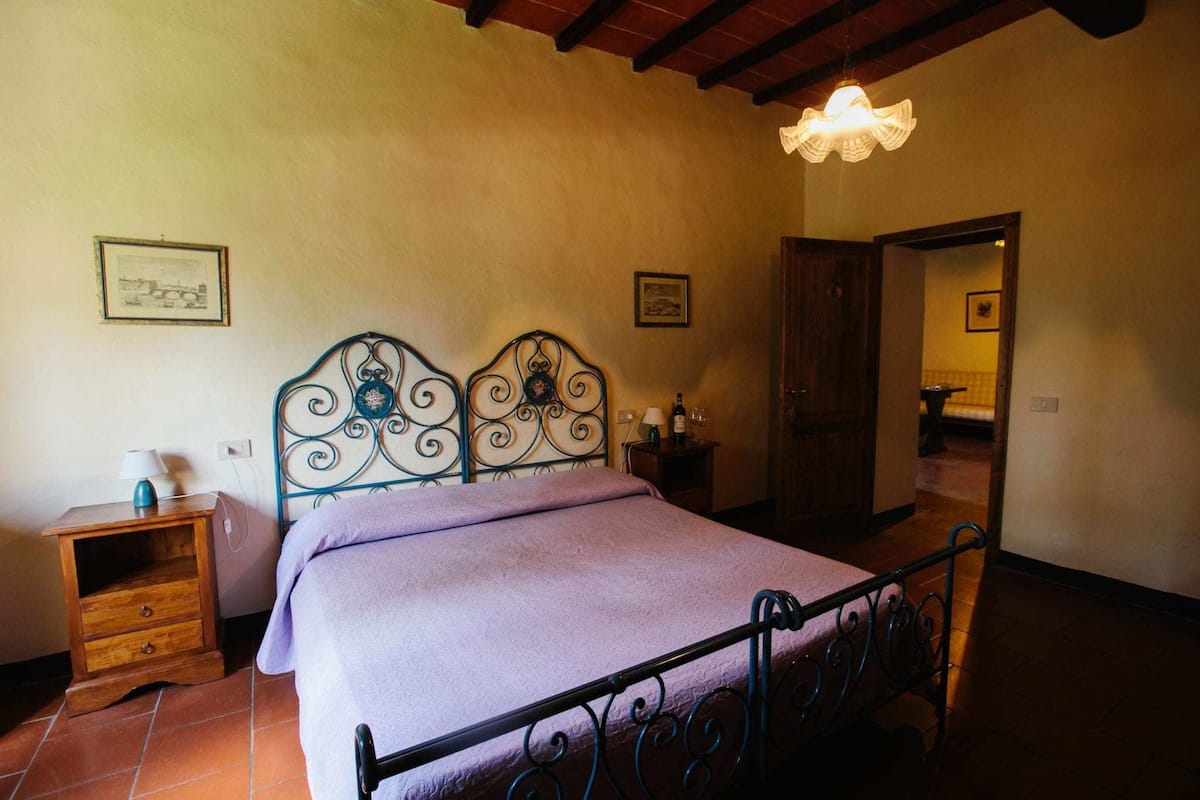 Quarto com uma cama, mesa de cabeceira, luminária e um quadro na parede.