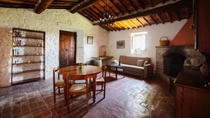 Una habitación rústica con una mesa de comedor de madera, un sofá, una chimenea y una estantería.