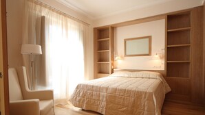 Une chambre à coucher comprenant un lit, une chaise, une table de chevet, un miroir et des étagères intégrées.