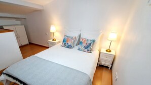 Quarto bem arrumado com uma cama grande, duas mesas de cabeceira com abajures e um guarda-roupa.