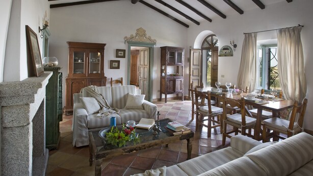 A spacious living room with a high ceiling, a dining area, and a kitchen visible through an open doorway. - Villa Cannigione (Palau)