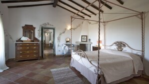 A bedroom with a four-poster bed, wooden dresser, and a mirror. - Villa Cannigione (Palau)