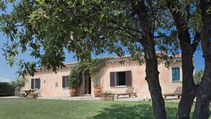A rustic villa with a tiled roof, a garden with a lawn, and outdoor furniture. - Villa Cannigione (Palau)