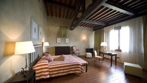 Une pièce comprenant un lit, deux chaises, une table et une cheminée.
