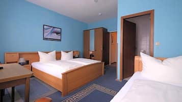 Ein Hotelzimmer mit einem Bett, einem Schreibtisch, einem Stuhl, einem Kleiderschrank und einer Tür zu einem anderen Raum.