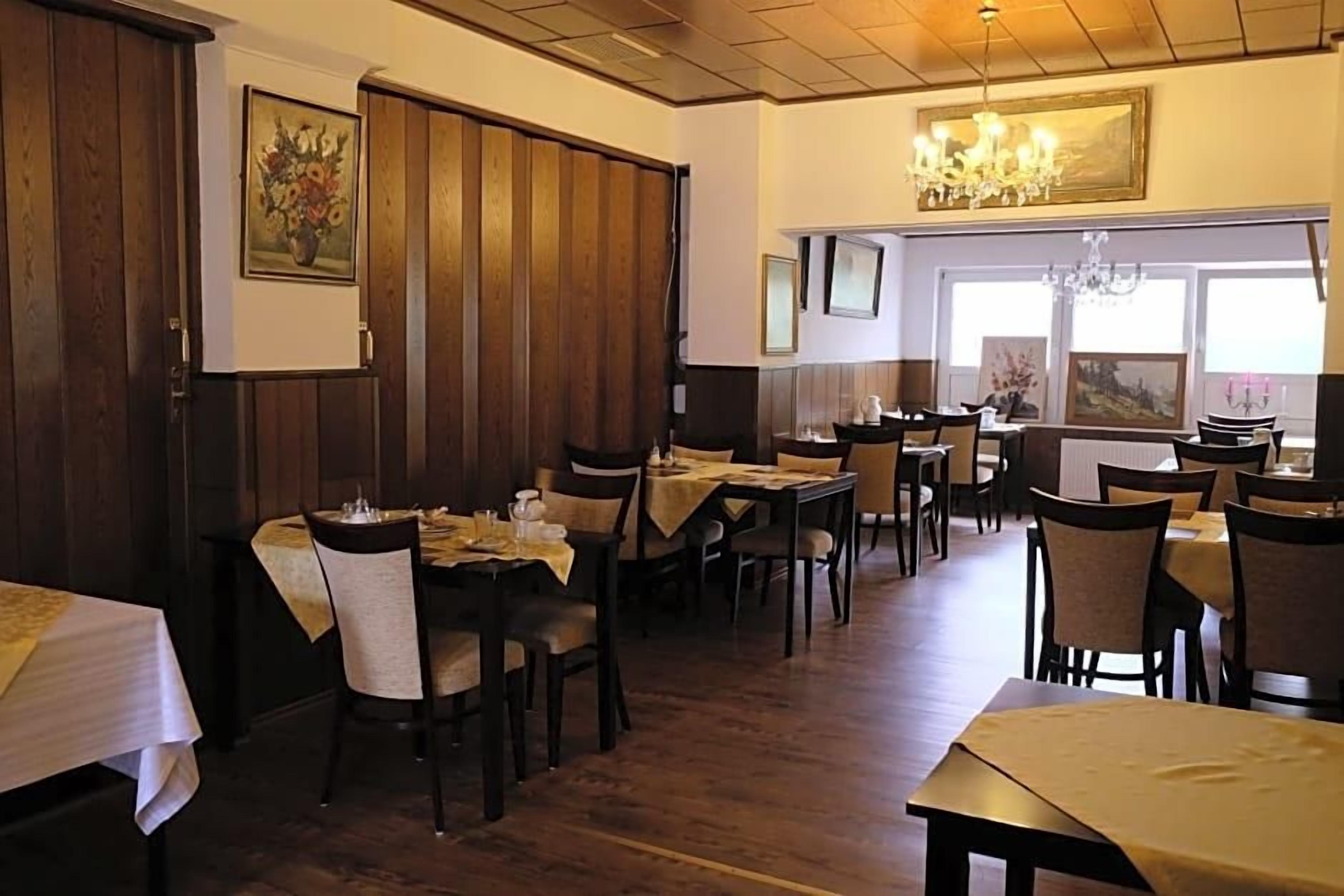 Ein Restaurant mit Holzwänden, mehreren Tischen, Stühlen und einer Kristallleuchter.
