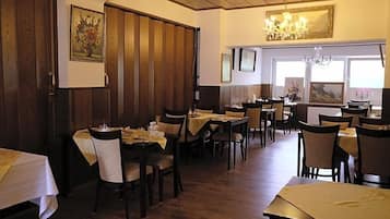 Ein Restaurant mit Holzwänden, mehreren Tischen, Stühlen und einer Kristallleuchter.