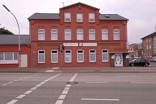 Un bâtiment en briques rouges, avec une enseigne indiquant « Hôtel-Restaurant Gruner Kranz », situé à un carrefour.