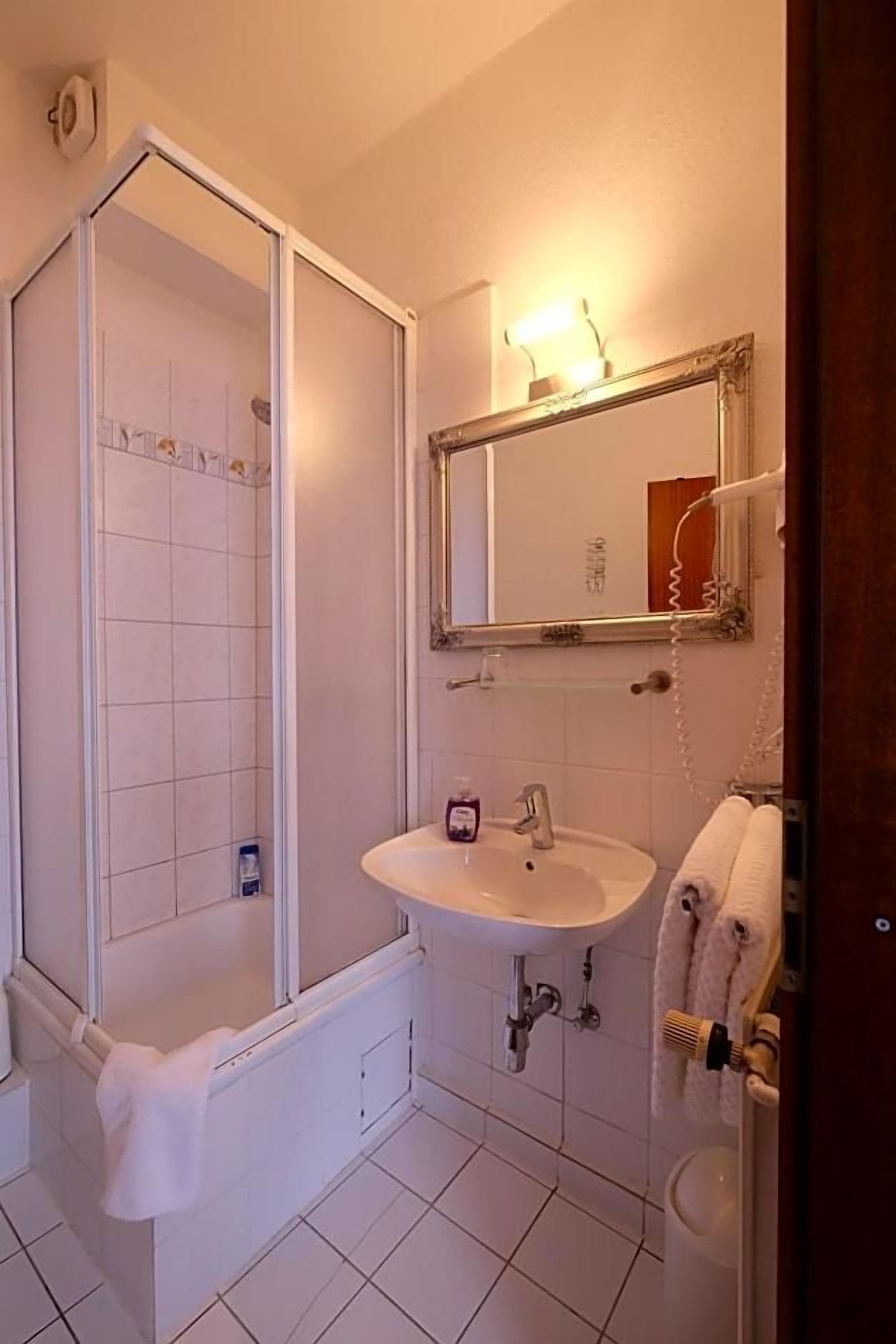 Ein Badezimmer mit Dusche, Waschbecken und Spiegel.