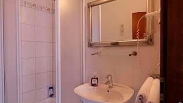 Ein Badezimmer mit Dusche, Waschbecken und Spiegel.
